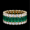 Gold ring with emeralds and diamonds on a black background