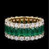 Gold ring with emeralds and diamonds on a black background